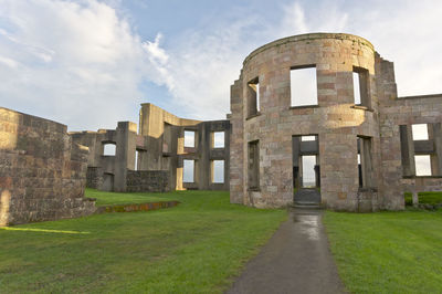 View of old building in field against cloudy sky