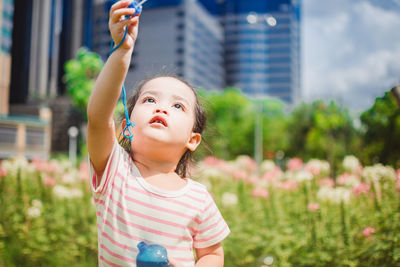 Girl holding bubble wand by flowers at park