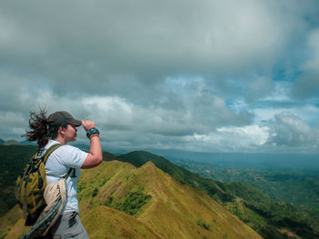 Man photographing on mountain against cloudy sky