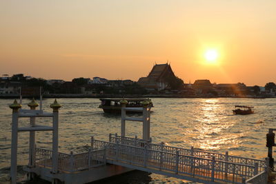 Bridge over river in city at sunset