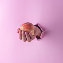 Close-up of hand holding apple against white background