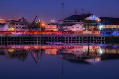 Illuminated industrial buildings with reflection on lake at night