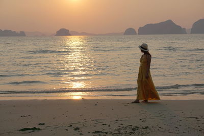 Woman on beach against sky during sunset