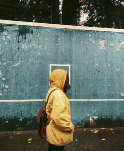 Side view of woman in raincoat standing on street