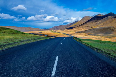 Road amidst landscape against blue sky