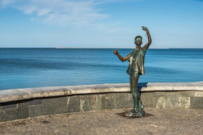 Statue on beach against sky