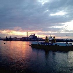 Boats at harbor against cloudy sky