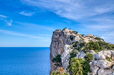 Rock formations by sea against blue sky