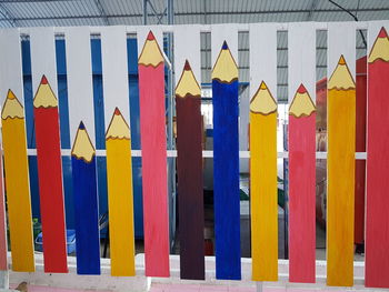 Close-up of multi colored flags hanging against blue wall