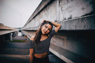 Portrait of smiling young woman standing against built structure