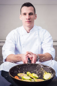 Chef preparing food while sitting against wall in restaurant