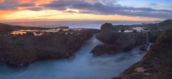 Scenic view of sea against cloudy sky during sunset