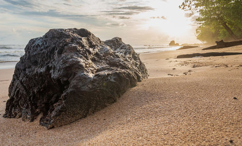 Rock formation on beach against sky during sunset