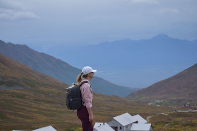 Rear view of man standing on mountain against sky