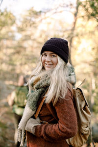 Side view of smiling young woman with backpack in forest