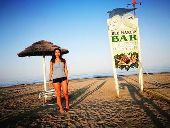 Woman standing on beach against clear sky