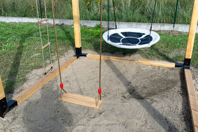 A modern cubic playground made of wooden logs and metal corners, a visible rocker and a nest.