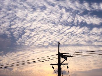 Low angle view of silhouette electricity pylon against sky