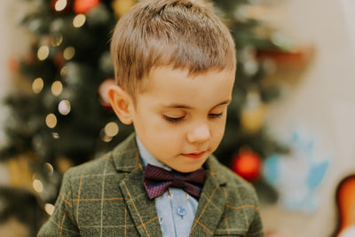 Cute boy wearing tuxedo and bow tie at home