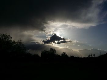 Silhouette of trees against cloudy sky