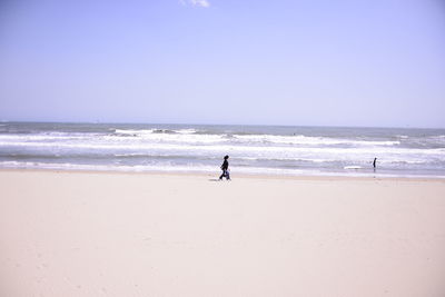 Man walking on beach against clear sky