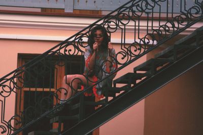 Portrait of young woman standing on staircase