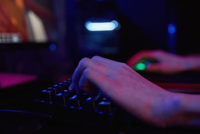 Gamer play computer game, use rgb neon colored keyboard