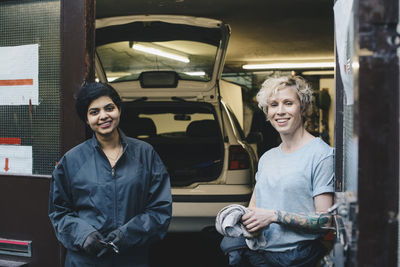 Portrait of female coworkers standing at entrance of auto repair shop