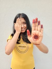 Portrait of smiling young woman standing against wall