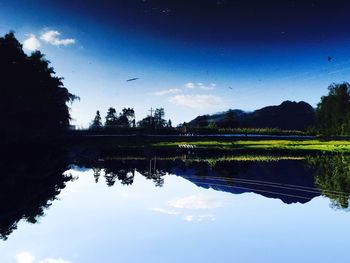 Reflection of trees in lake against blue sky