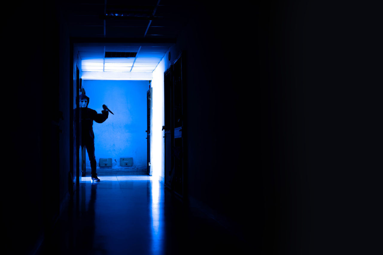 SILHOUETTE MAN LOOKING AT ILLUMINATED BUILDING