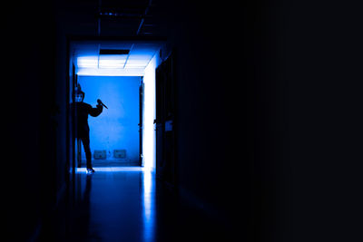 Silhouette man in illuminated corridor of building