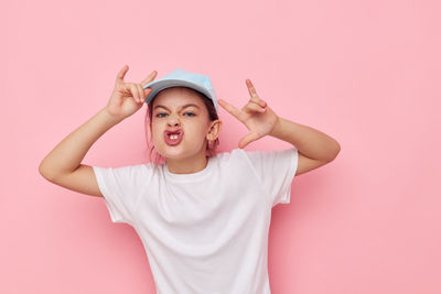 Portrait of young woman against pink background