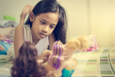 Little girl is playing dolls on bed in a holiday.