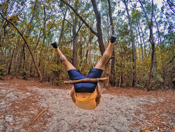 Young man hanging upside down in forest