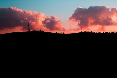 Silhouette landscape against dramatic sky during sunset