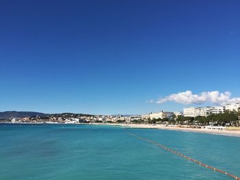 Scenic view of sea and buildings against clear blue sky