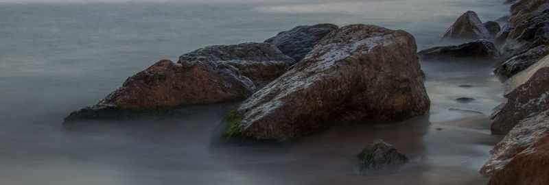 Rock formation in sea against sky