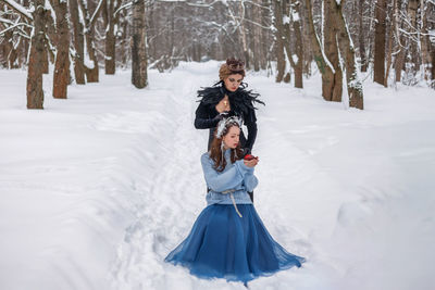 Full length of woman standing on snow covered field