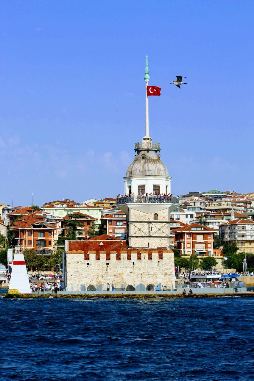 architecture, building exterior, built structure, sky, building, water, waterfront, nature, flag, city, day, tower, travel destinations, no people, clear sky, sea, blue, travel, the past, outdoors, lighthouse