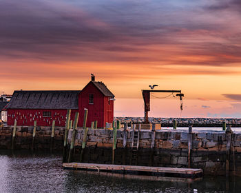 Houses by canal against sky during sunset