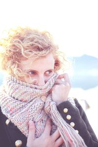 Young woman covering face with scarf during winter