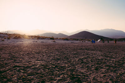 Desert by mountains against sky during sunset