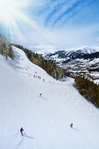 People skiing on snowcapped mountain against sky