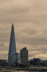 Modern buildings in city against cloudy sky