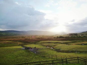 Scenic view of grassy field against cloudy sky