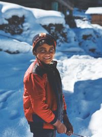 Portrait of smiling woman standing on snow covered landscape