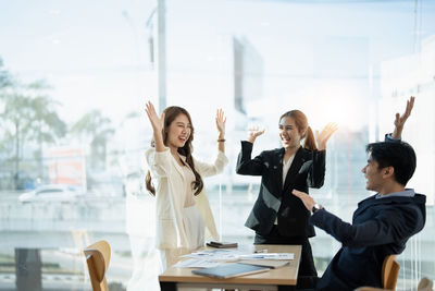 Portrait of female friends using mobile phone while sitting at office