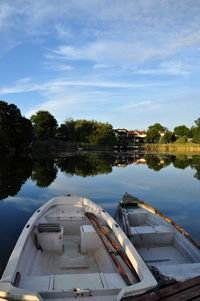 Boats moored on river by trees against sky