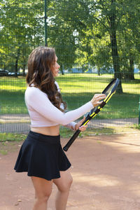 Side view of young woman standing against trees